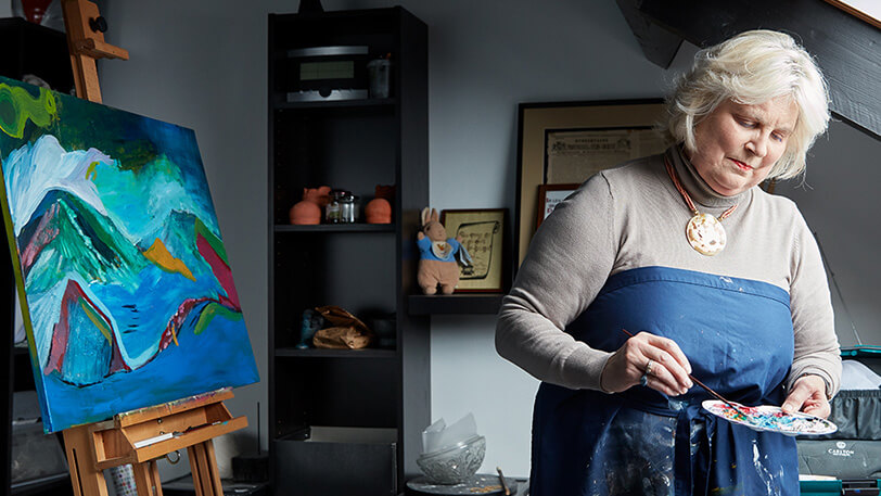 Vrouw die palliatieve zorg krijgt, zit bij het raam in haar woonkamer